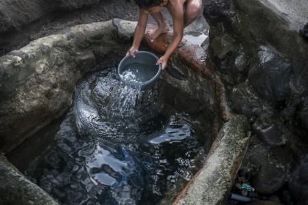November 07, 2014. "Water it´s the real thing" A child takes water from a well contaminated in Nejapa (El Salvador). The people of Nejapa in El Salvador, have no drinking water because the Coca -Cola company overexploited the aquifer in the area, the most important source of water in this Central American country. This means that the population has to walk for hours to get water from wells and rivers. The problem is that these rivers and wells are contaminated by discharges that makes Coca- Cola and other factories that are installed in the area. The problem can increase: Coca Cola company has expansion plans, something that communities and NGOs want to stop. To make a liter of Coca Cola are needed 2,4 liters of water. ©Calamar2/ Pedro ARMESTRE